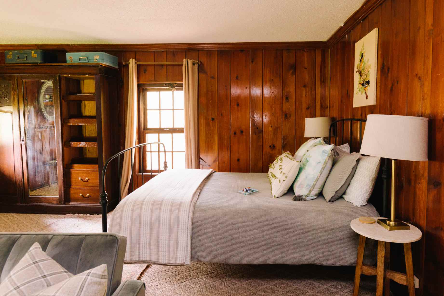The Cabin Greenville bedroom with iron bed frame and knotty pine walls